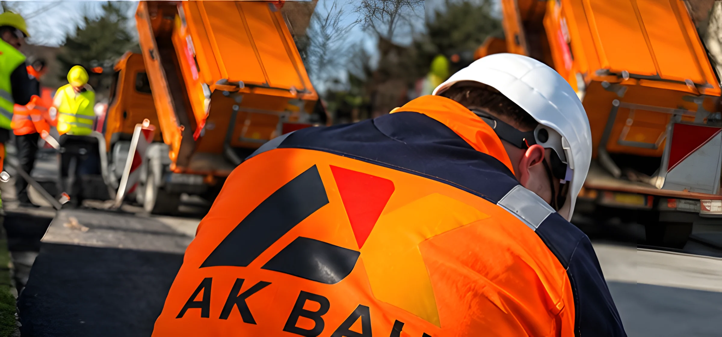 AK-BAU-Mitarbeiter in orangefarbener Warnkleidung auf einer Baustelle